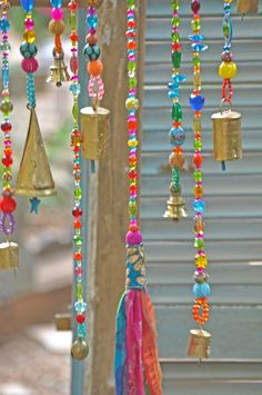 several bells hanging from a building with colorful beads