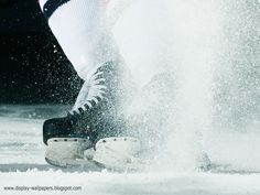 a person in white and black ice skates on the ice with splashing snow around them