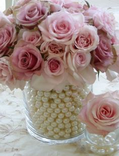 a vase filled with pink roses and pearls