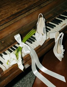 the bride's shoes and bouquet are sitting on the piano keys, which is adorned with satin ribbons