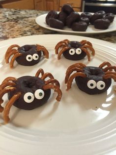 chocolate covered donuts decorated with googly eyes and spider legs on a plate in the kitchen