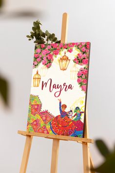 an easel with a sign that says mayra on it and flowers in the background