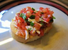 an open faced sandwich with tomatoes, cheese and lettuce on it sitting on a plate