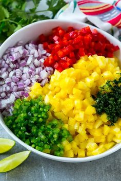 a bowl filled with chopped up vegetables next to sliced limes and cilantro