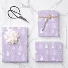 the wrapping paper is purple and white with snowflakes on it, along with scissors