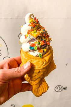 a hand holding an ice cream cone filled with candy