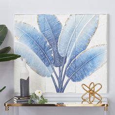 a blue and white painting on a wall next to a table with a plant in it