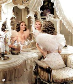 an old fashion photo of three women sitting at a table in front of a mirror