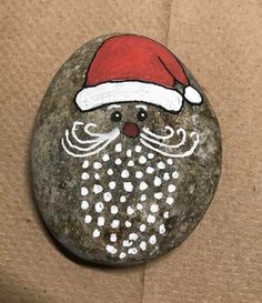 a painted rock with a santa hat and beard