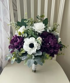 a bouquet of flowers sitting on top of a white table next to a window curtain