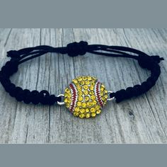 a baseball bracelet with yellow and red beads on a black cord that is sitting on a wooden surface