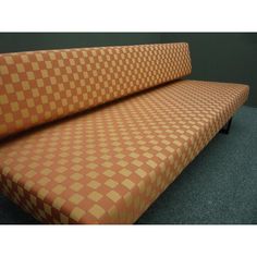 an orange and brown checkered couch sitting on top of a blue carpeted floor