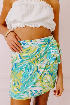 - Piña Coladas are calling with this vibrant skirt! - Fully lined material with an abstract botanical print featuring different blue and green hues - A waistline with side zip closure - A wrap style front with side tie closure - A figure flattering silhouette that ends in a mini skirt length hemline Linen Mini Skirt, Abstract Botanical, Green Hues, Botanical Print, Botanical Prints, Skirt Length, Wrap Style, Side Zip, Mini Skirt