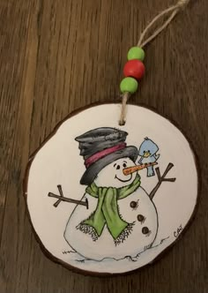 a wooden ornament with a snowman painted on it