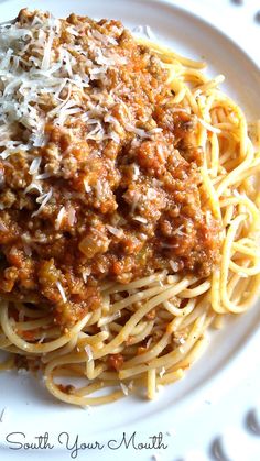 a plate of spaghetti with meat sauce and parmesan cheese on top, ready to be eaten