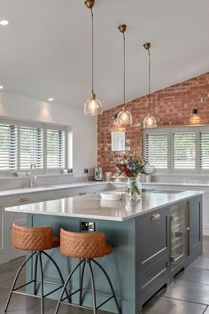 a kitchen with two stools in front of an island and brick wall behind it