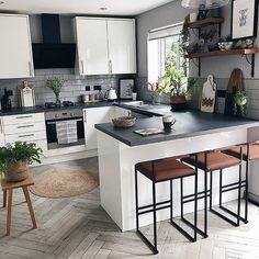 a kitchen with white cabinets and black counter tops, wooden flooring and an island in the middle