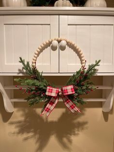 a christmas wreath hanging on the side of a white cabinet