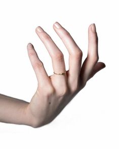 a person's hand with a gold ring on their left wrist and fingers extended out