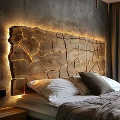 a bed that has some lights on the headboard and pillows in front of it