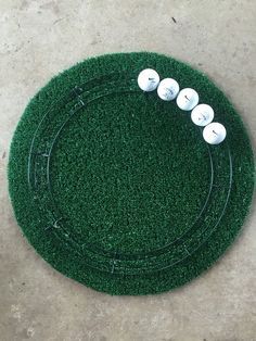 four white golf balls sitting on top of a green grass covered field with holes in the middle