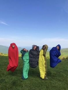 four people in colorful sleeping bags on top of a hill