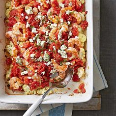 a square casserole dish with shrimp, tomatoes and feta cheese on top