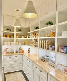 a kitchen filled with lots of white cupboards and counter top space next to a light fixture