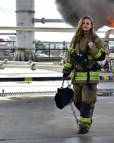 a woman in firefighter gear walking down the street with her hand on her hip