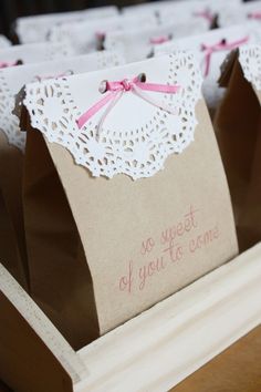 some paper bags that are sitting on a table with pink bows and lace around them