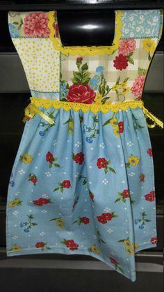 a blue dress with flowers on it hanging from a stove top oven door knobs