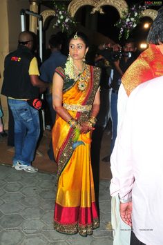 a woman in a yellow and red sari standing next to a man wearing a white shirt