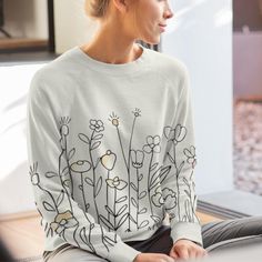 Bloom in Comfort with Our Floral Crewneck Sweatshirt - Soft Ivory Bliss Elevate your cozy wardrobe with this charming all-over print crewneck sweatshirt, featuring a delicate floral design that's perfect for nature lovers. The soft, ivory-toned fabric adds a fresh and neutral touch, making it easy to pair with any outfit while keeping your style effortlessly chic. Whether you're relaxing at home or stepping out for a casual day, this medium-weight sweatshirt offers the perfect balance of warmth and comfort. Crafted from 100% polyester and custom cut and sewn, this crewneck ensures a classic fit with set-in sleeves that feel as good as they look. Ideal for layering or wearing on its own, the minimalist flower pattern adds a pop of personality to your everyday look. Get ready to bloom in sty Cream Floral Print Crew Neck Top, Spring Cream Graphic Sweatshirt, Spring Cream Graphic Print Sweatshirt, Cozy Graphic Print Sweatshirt For Spring, Cream Graphic Print Sweatshirt For Spring, Cream Long Sleeve Sweater With Floral Print, Cozy Graphic Print Tops For Spring, White Floral Print Cotton Sweater, White Floral Print Casual Sweatshirt