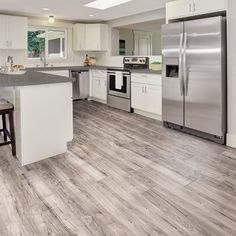 a large kitchen with white cabinets and stainless steel appliances, along with hardwood flooring