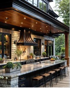 an outdoor kitchen with lots of counter space and lights on the ceiling, along with bar stools