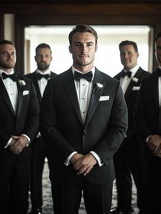 a group of men in tuxedos standing next to each other with their hands on their hips