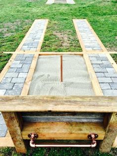 a table made out of wood and metal pipes on top of it in the grass