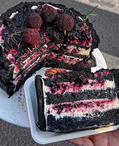 a piece of cake on a plate with strawberries and black raspberry filling