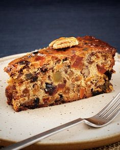 a piece of fruit cake on a plate with a fork and knife next to it