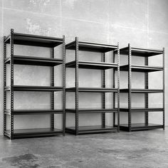 three empty shelvings are lined up against the wall in an empty room with concrete flooring