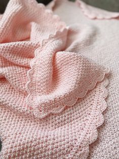 a pink knitted blanket laying on top of a bed