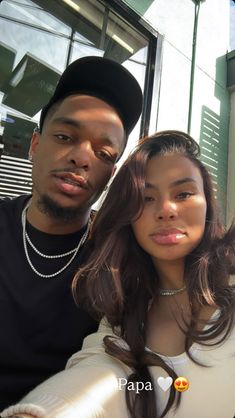 a young man and woman posing for a photo together in front of a store window