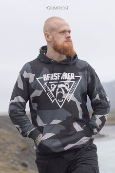 Premium pullover hoodie in the famous M90 camo pattern used by the Swedish Armed Forces. It is custom-made for Grimfrost in soft, luxurious organic cotton. The hoodie comes with a zipped utility pocket on the left arm, spacious kangaroo pouch pockets and drawstring eyelets with a Younger Futhark runic circle. "Berserker", Valknut and roaring bear print. The Valknut is a symbol of Odin, the god of the Berserker. The bear represents the state of mind of the raging Berserker. #viking #grimfrost M90 Camo, Roaring Bear, Younger Futhark, Swedish Armed Forces, Viking Men, Viking Clothing, Viking Designs, Grey Camo, Bear Hoodie