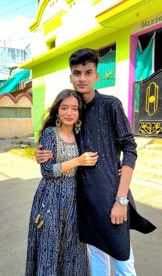 a man and woman standing next to each other in front of a building with colorful walls