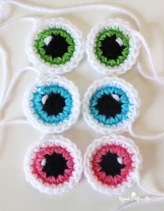 four crocheted eyeballs sitting on top of a white table