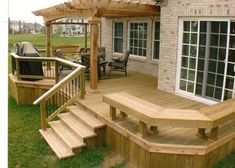 a wooden deck with steps leading up to the back door and an attached pergolan