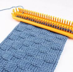 a close up of a knitted piece of cloth next to a yellow comb