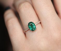 a close up of a person's hand with a green ring on their finger