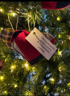 a christmas ornament hanging from the top of a tree with a note attached to it