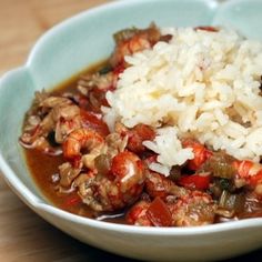 a bowl filled with meat and rice on top of a wooden table